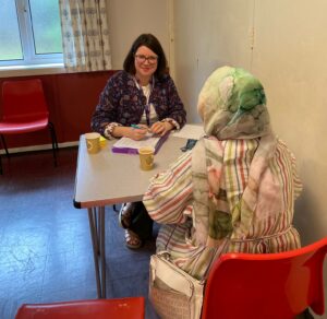 2 people, seated at a table, talking to each other at one of our engagement events