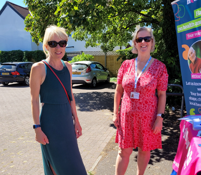 One of our staff with a patient of a local practice - they are stood outside beside a Healthwatch Surrey banner.